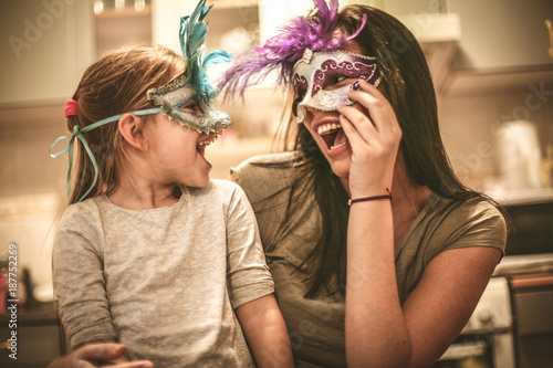 Mother and daughter have play with carnival mask.