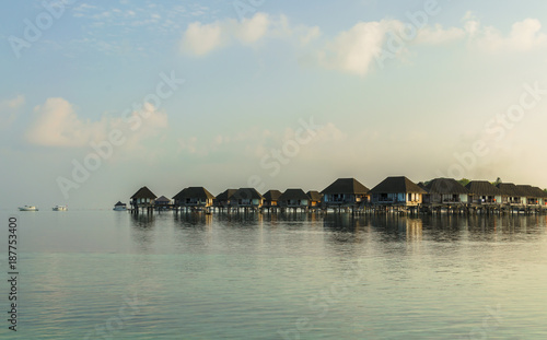 Вeautiful wooden villas, standing on stilts in the middle of turquoise water of the Indian Ocean, sunrise, Maldives. Travel and tourism concept