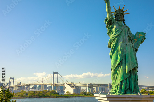 Close up of Statue of Liberty and Rainbow Bridge, icons of Odaiba Island in Tokyo, Japan. Replica of famous Statue of Liberty of New York. Tokyo skyline and skyscrapers on background. photo