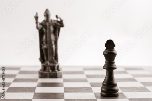 Classic black king and the same chess piece in the form of medieval figure on the background