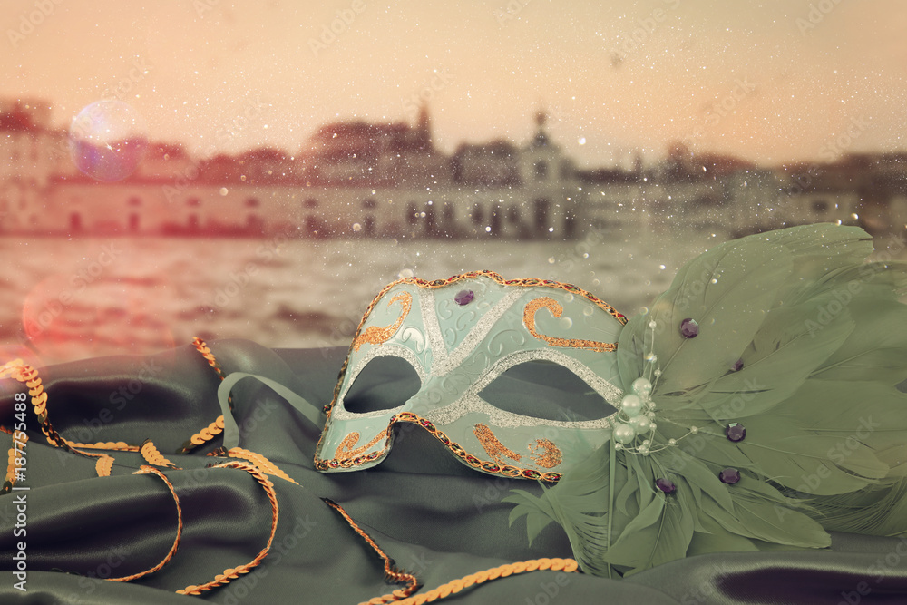 Fototapeta Wizerunek elegancka venetian maska ​​na jedwabniczej tkaninie przed rozmytym Wenecja tłem.