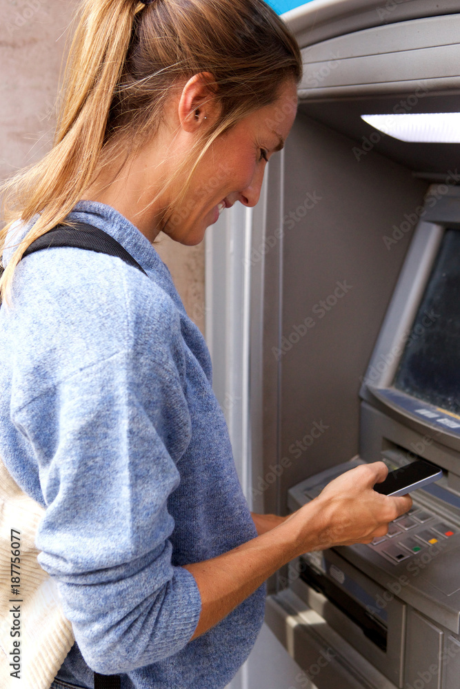 young woman with mobile phone by bank machine young woman with mobile phone by bank machine