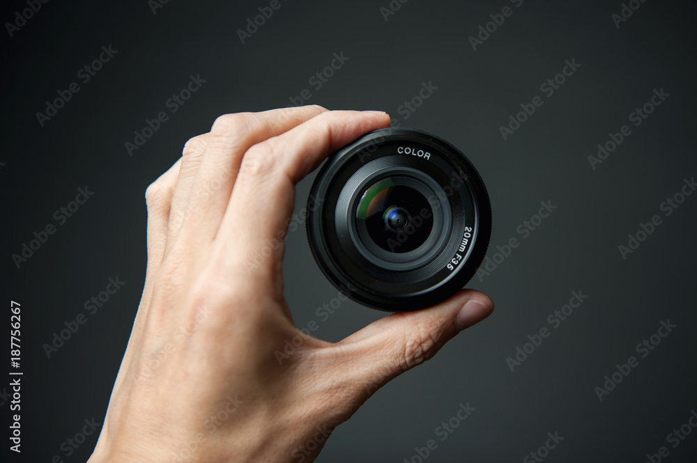man's hand holding a camera lens on a black background man's hand holding a camera lens on a black background