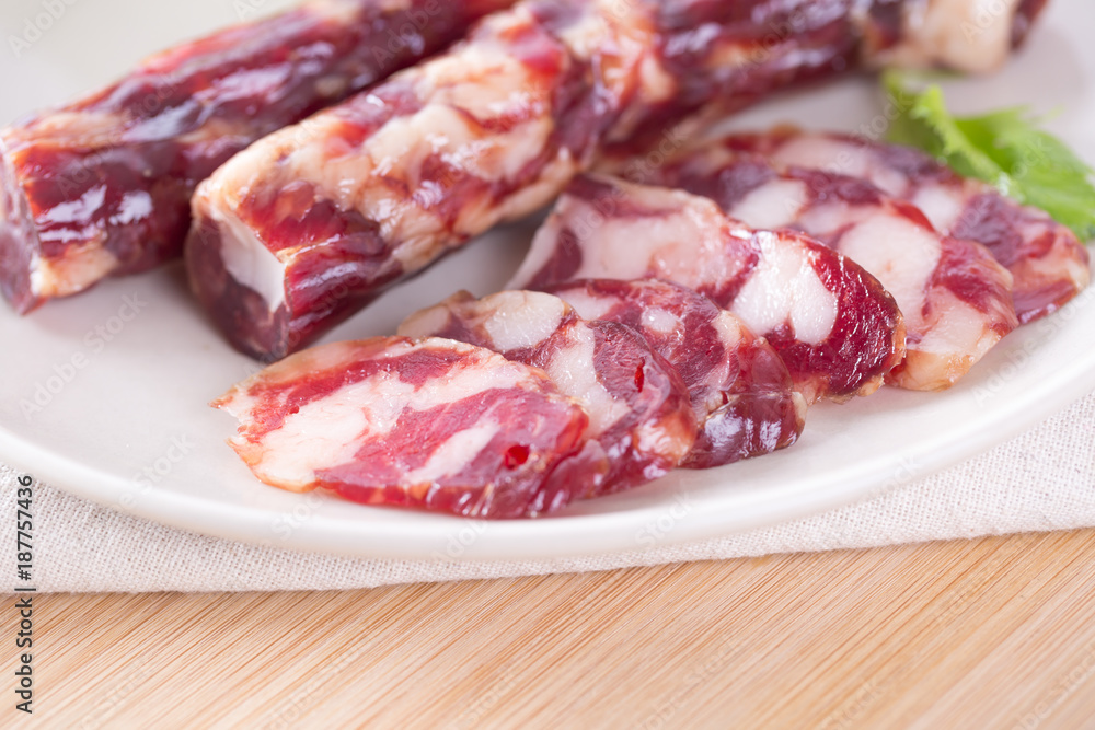 Close-up of cold cuts and vegetables on a plate. Raw pork sausage. Close-up of cold cuts and vegetables on a plate. Raw pork sausage.