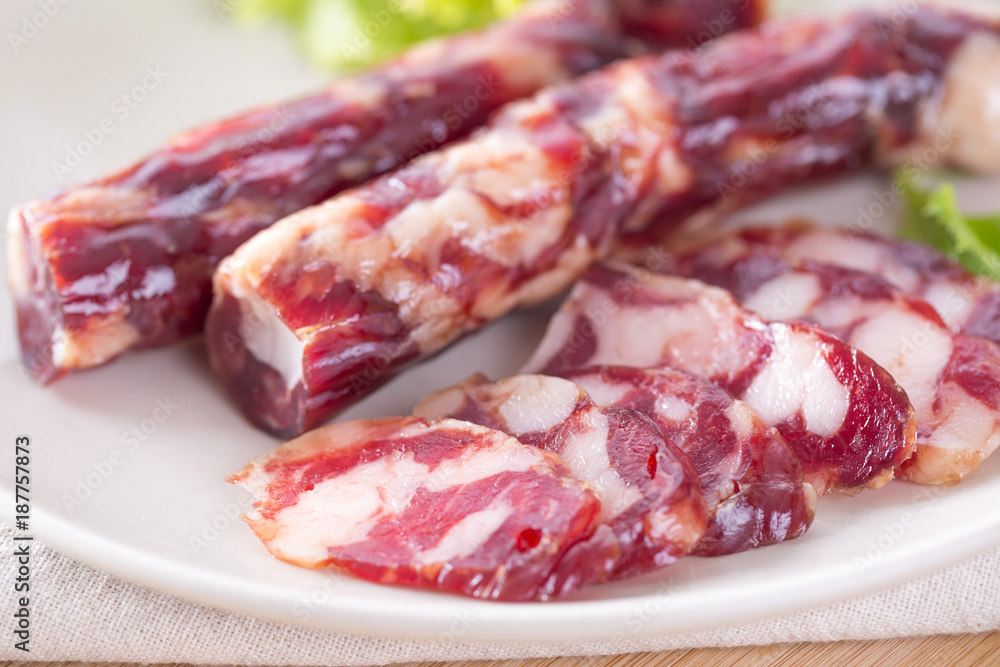 Close-up of cold cuts and vegetables on a plate. Raw pork sausage. Close-up of cold cuts and vegetables on a plate. Raw pork sausage.