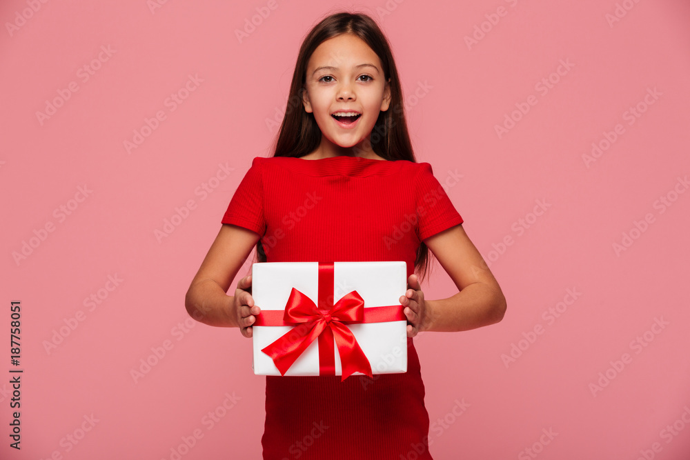 Cheerful girl showing gift and smiling isolated over pink Cheerful girl showing gift and smiling isolated over pink