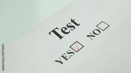 close-up hand filling yes and no at the checklist box with red pencil photo