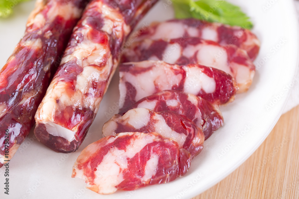 Close-up of cold cuts and vegetables on a plate. Raw pork sausage. Close-up of cold cuts and vegetables on a plate. Raw pork sausage.
