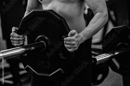Male hand choosing a weight on a metal weights of bodybuilding equipment in a gym.