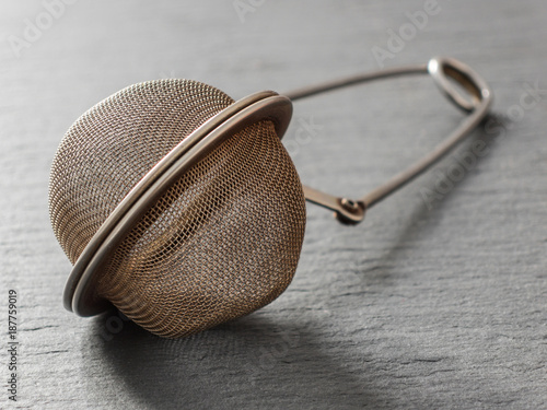 Round metal tea strainer for brewing tea on a black background