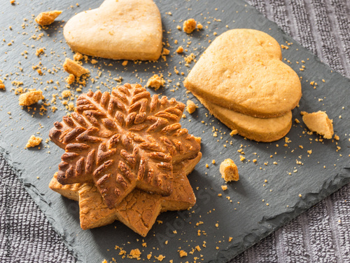 Yellow ginger biscuits in the shape of snowflakes and hearts on a black background
