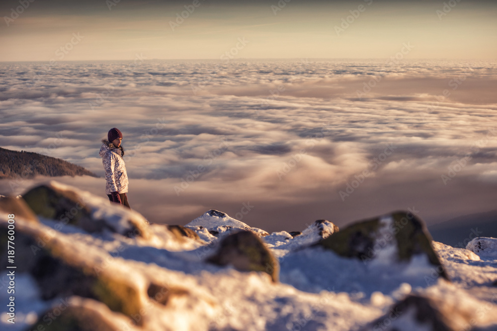 pretty woman on top of mountain, female hiker admiring winter scenery on a mountaintop alone