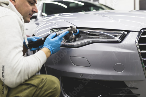 Car detailing - Worker with orbital polisher in auto repair shop.