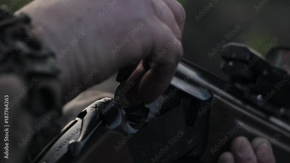 Smoke from the trunks of smooth-bore hunting rifle after firing. Hunter in camouflage takes out cartridges from a gun. Smoke from the trunks of smooth-bore hunting rifle after firing. Hunter in camouflage takes out cartridges from a gun.