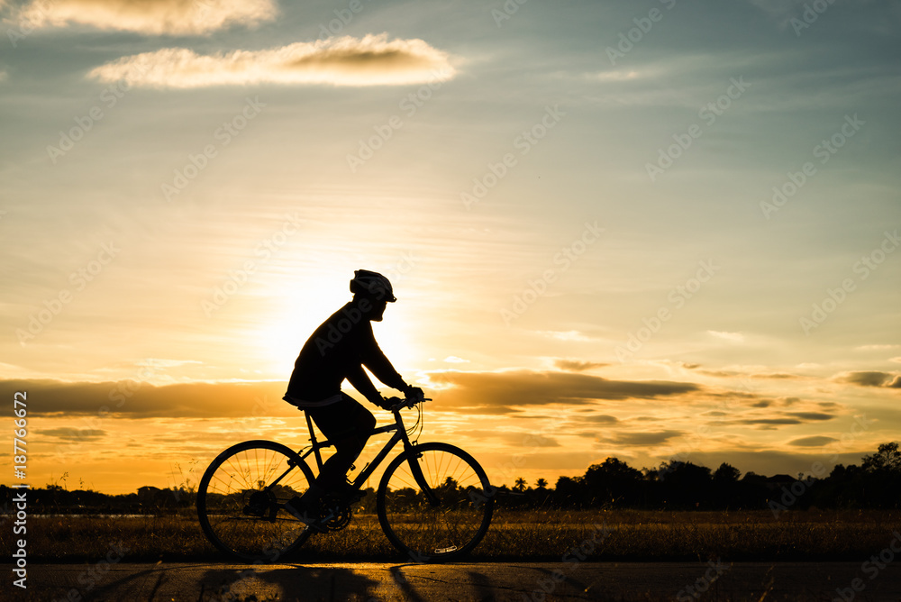 Fototapeta premium Silhouette man cycling at sunset