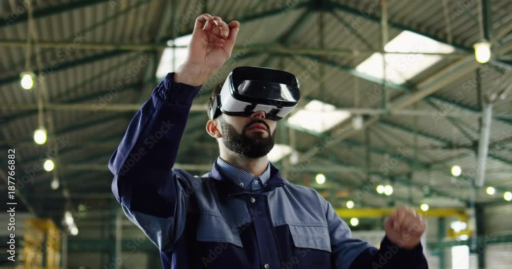 Male engineer having VR headset in a big factory room. Worker in VR glasses. Indoors. Portrait shot Male engineer having VR headset in a big factory room. Worker in VR glasses. Indoors. Portrait shot