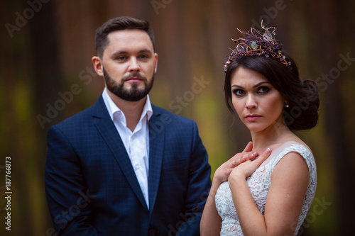 portrait of brutal bride and groom in wooden crown on background of trees
