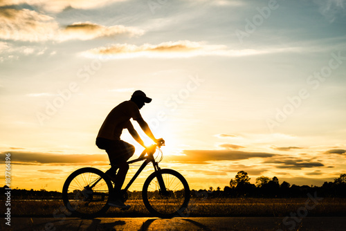 Silhouette man cycling at sunset © songdech17
