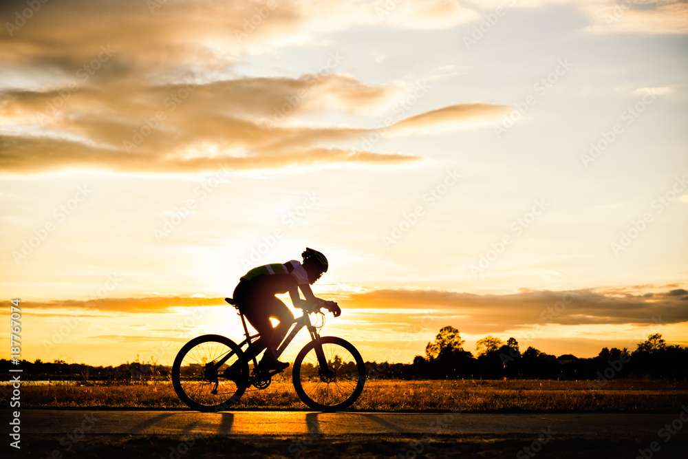 Silhouette man cycling at sunset