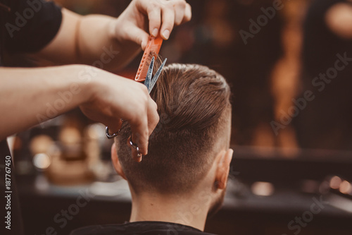 Close-up, master hairdresser does hairstyle and style with scissors and comb. Concept Barbershop.