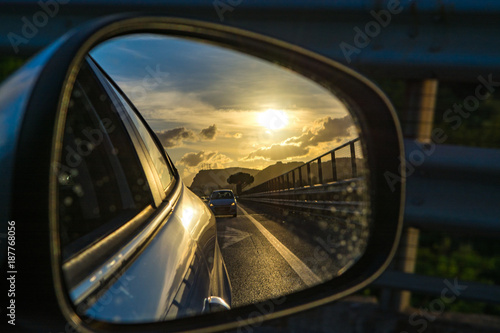 Transportation in Italy, highway on Sicily, view from the cars mirror on sunset