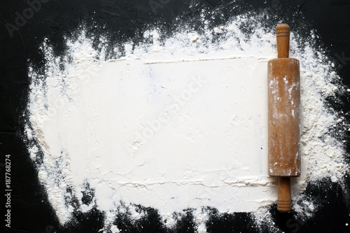 white flour with a rolling pin on a black background