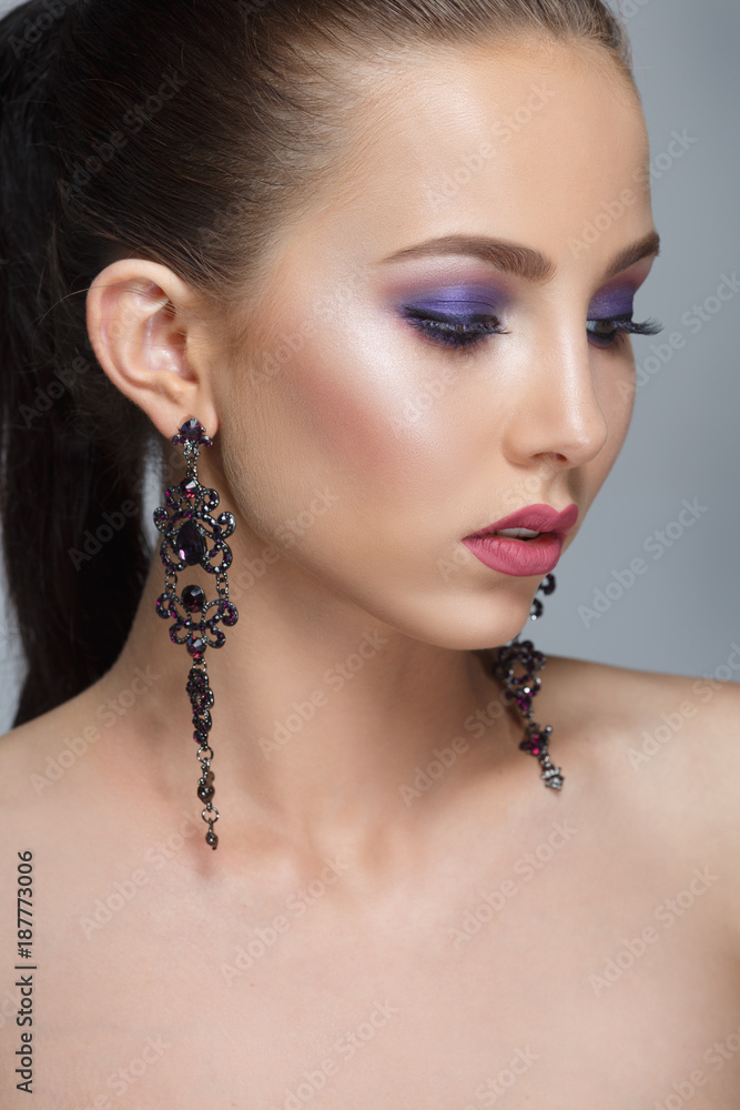 Fashion beauty portrait of a beautiful girl with a lilac make-up isolated on a gray background.