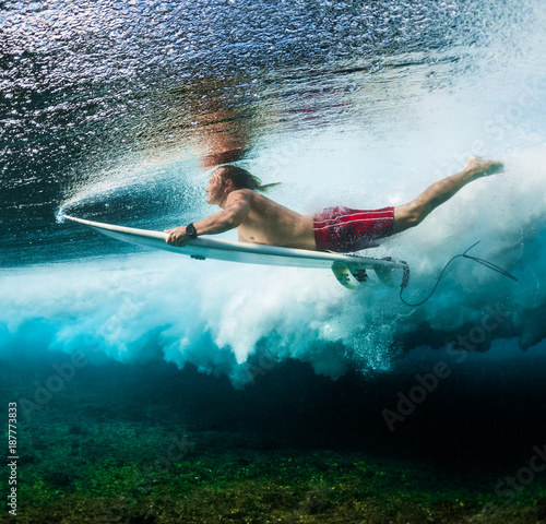 Photography Young surfer dives under the ocean wave with surf board and performs trick named