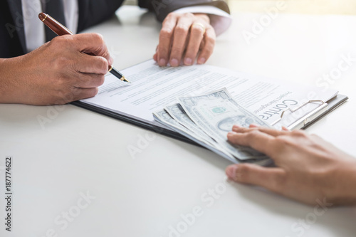 Bribery and corruption concept, bribe in the form of dollar bills, Businessman giving money while making deal to agreement a real estate contract and financial corporate