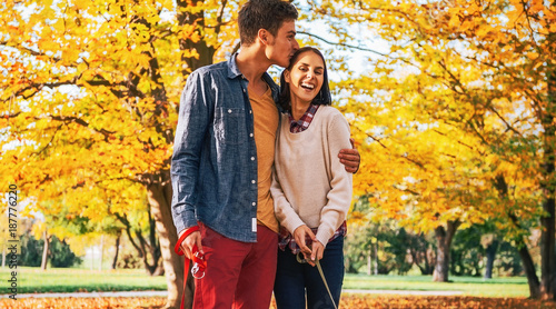 Canvas Print Romantic young couple walking outdoors in autumn park with dogs