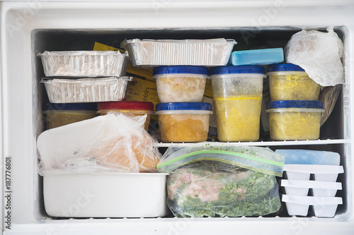 a freezer packed with chicken, soup and various frozen food
