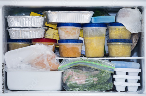 a freezer packed with chicken, soup and various frozen food