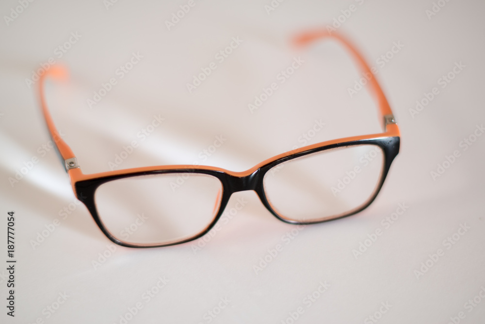 glasses in an orange frame on a white background. Selective focus. Close up glasses in an orange frame on a white background. Selective focus. Close up
