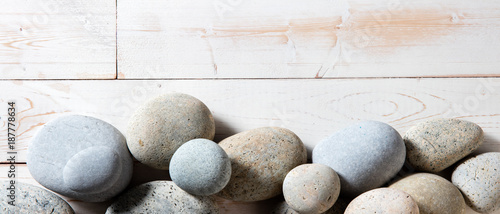 Photo border of grey zen stones set on white wooden background