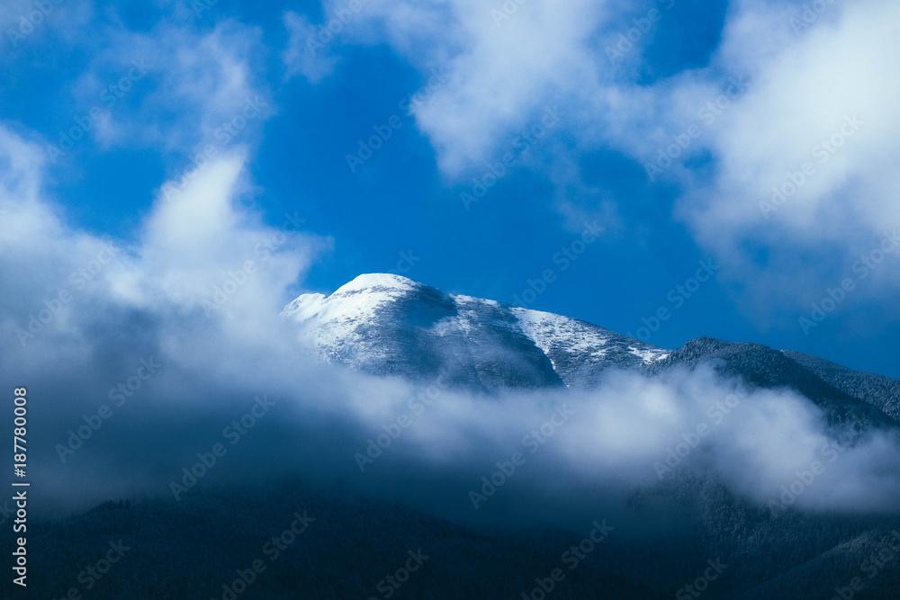 Beautiful foggy mountains high peaks covered with snow and ice. Morning winter alpine landscape, fog clouds, beautiful natural winter backdrop. Beautiful foggy mountains high peaks covered with snow and ice. Morning winter alpine landscape, fog clouds, beautiful natural winter backdrop.