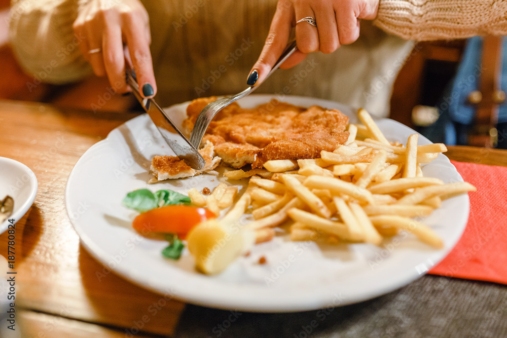 Woman with fork and knife to eat french fries with chicken in a restaurant Woman with fork and knife to eat french fries with chicken in a restaurant