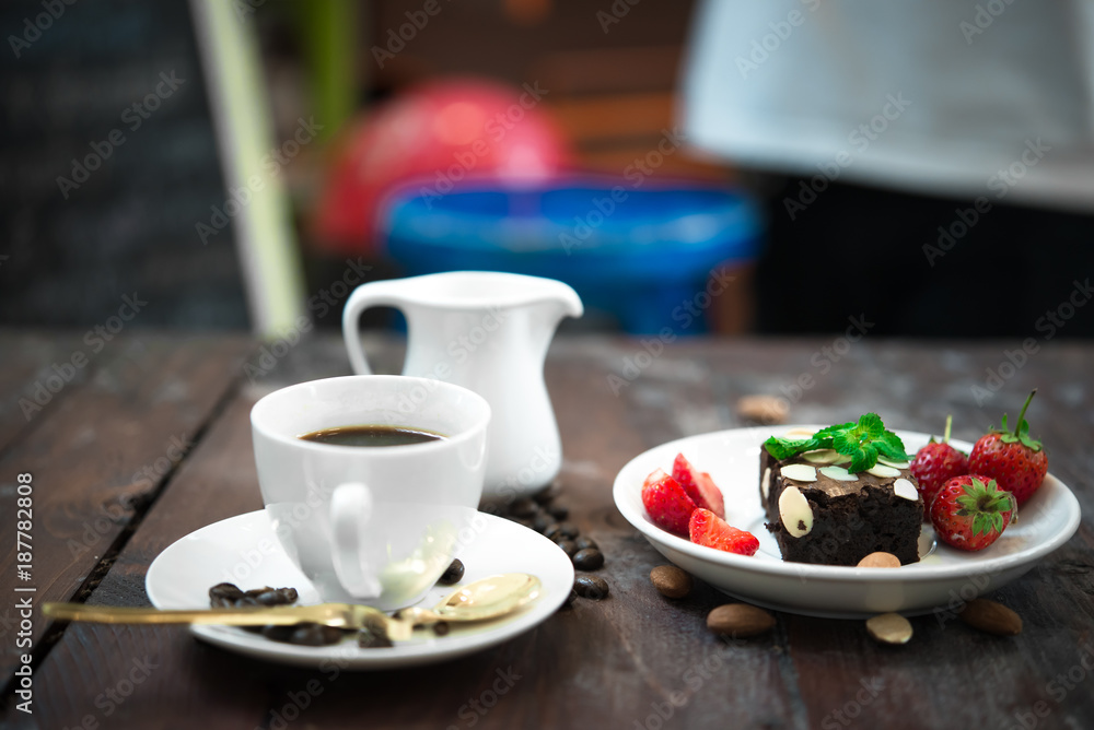 Brownie with Fresh strawberry on white plate,Hot coffee on wood background Brownie with Fresh strawberry on white plate,Hot coffee on wood background