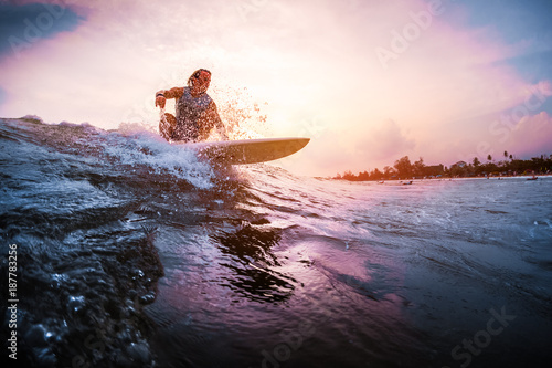 Surfer rides the ocean wave during sunset. Extreme sport and active lifestyle concept