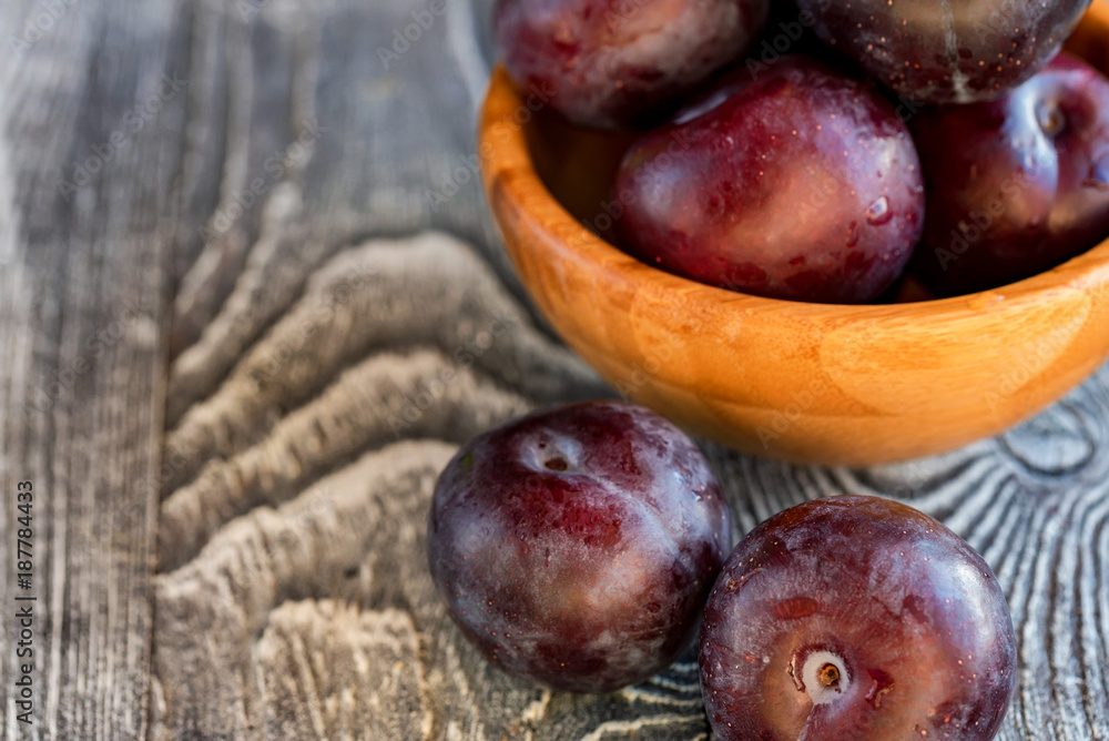 Obraz premium Garden plums in bowl on wooden table