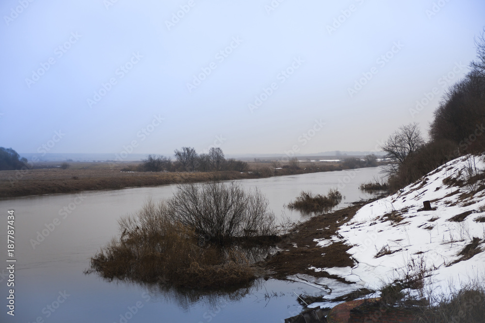 Fototapeta premium small spring river with snow along coast