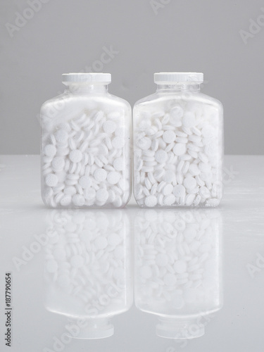 White tablets in white containers, white background 