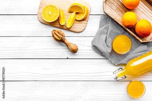 Make orange juice. Juicer  beverage in bottle and glasses near slices of oranges on white wooden background top view copy space