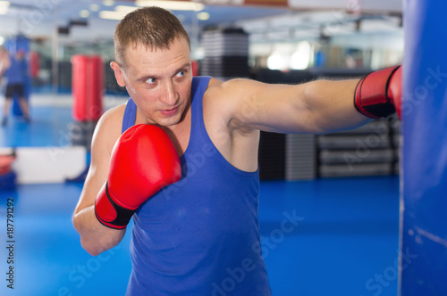 Active male is training with punching bag in box gym © JackF