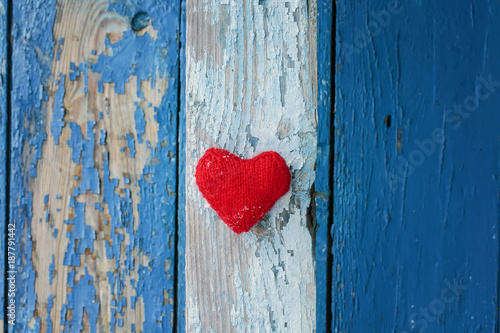 red heart made of yarn against the wall of wood with a shabby country blue paint different shades of stripes