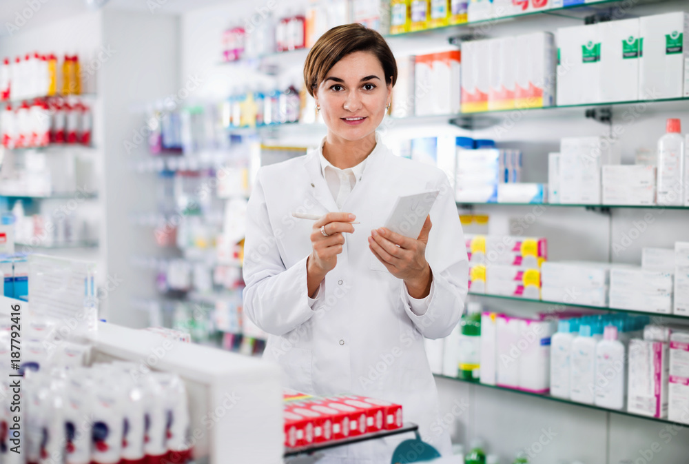 Female pharmacist noting assortment of drugs