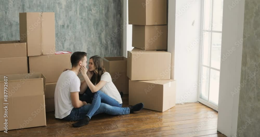 Young couple relaxing laughing after unpacking cartons from house move Young couple relaxing laughing after unpacking cartons from house move