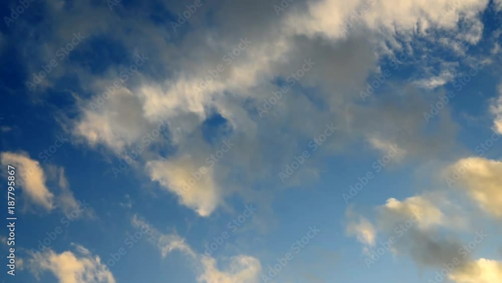 Сlouds in the sunset light against the blue sky. Slow motion.
