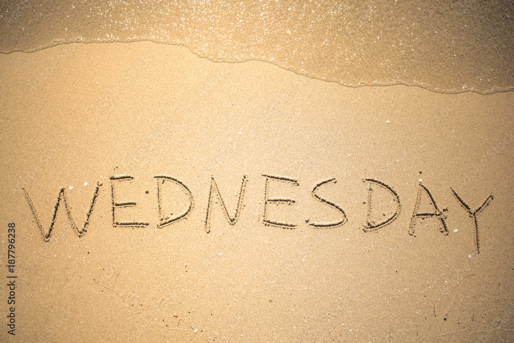 Fototapeta premium Wednesday word is written on the beach sand