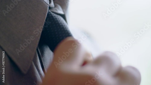 Close-up of hispanic man getting ready tying a necktie in the morning