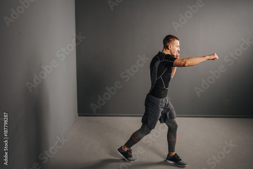 Athletic man make punch. Handsome fitness model show muscular body. Strong hands, shoulder muscles and biceps. Studio shot on grey background, low key. Kickboxing and fight sport concept